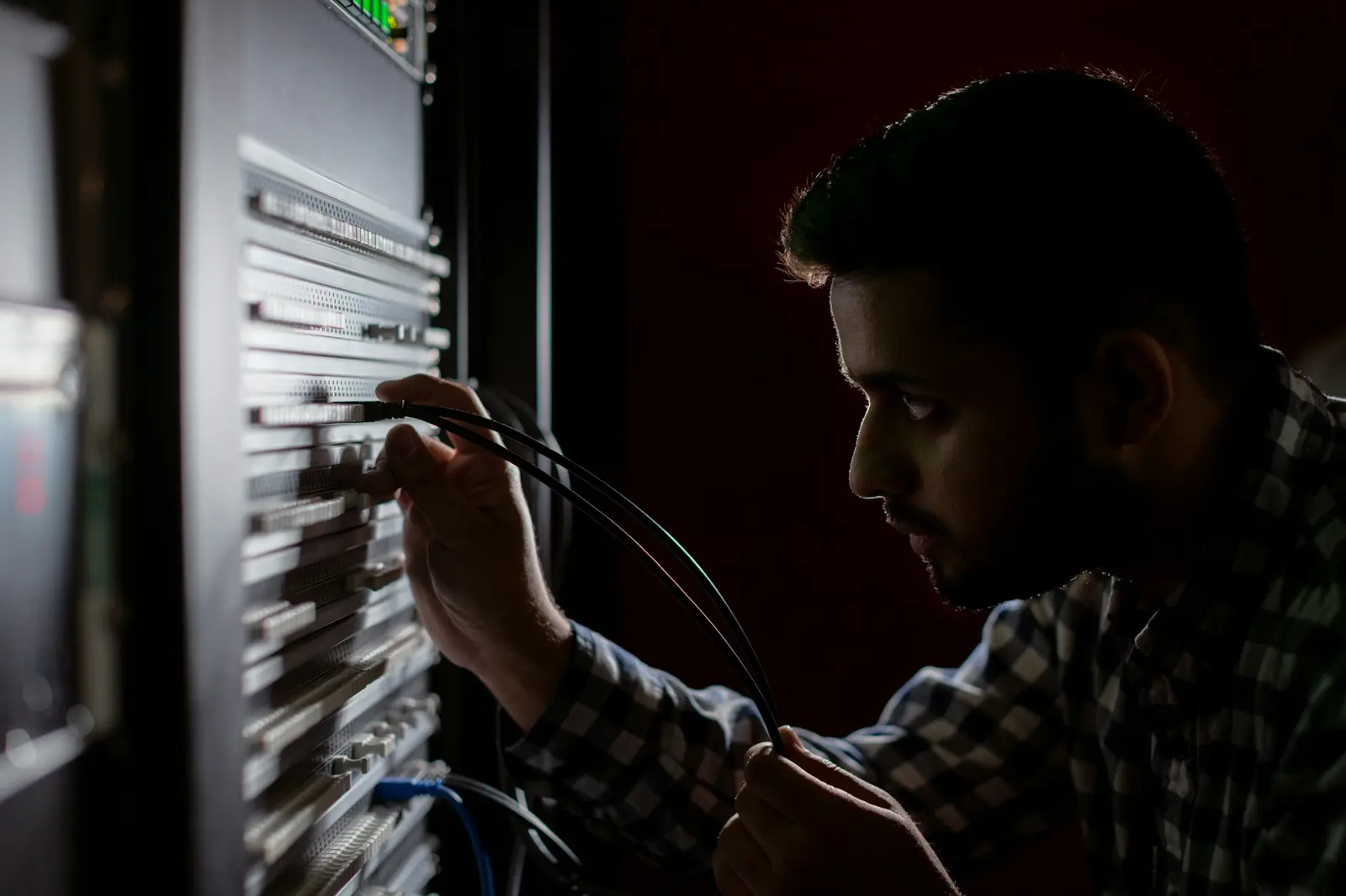 A technician plugging network cables into a rack