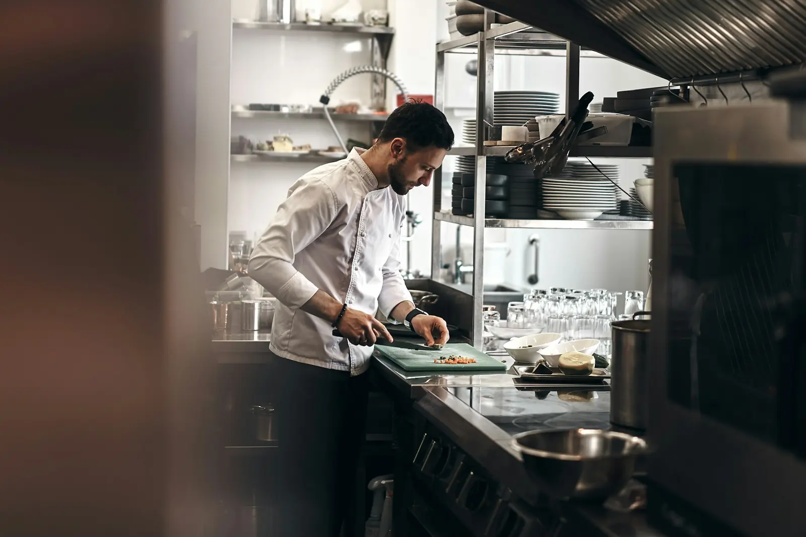 A chef slicing vegetables in a busy restaurant kitchen