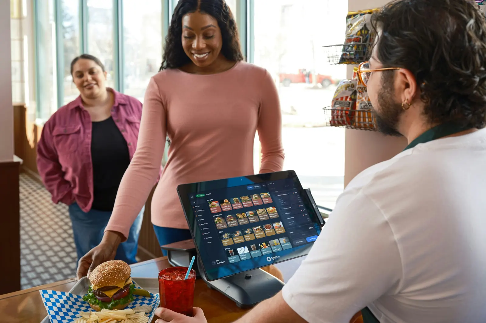 A cashier taking an order on a tablet at a restaurant counter