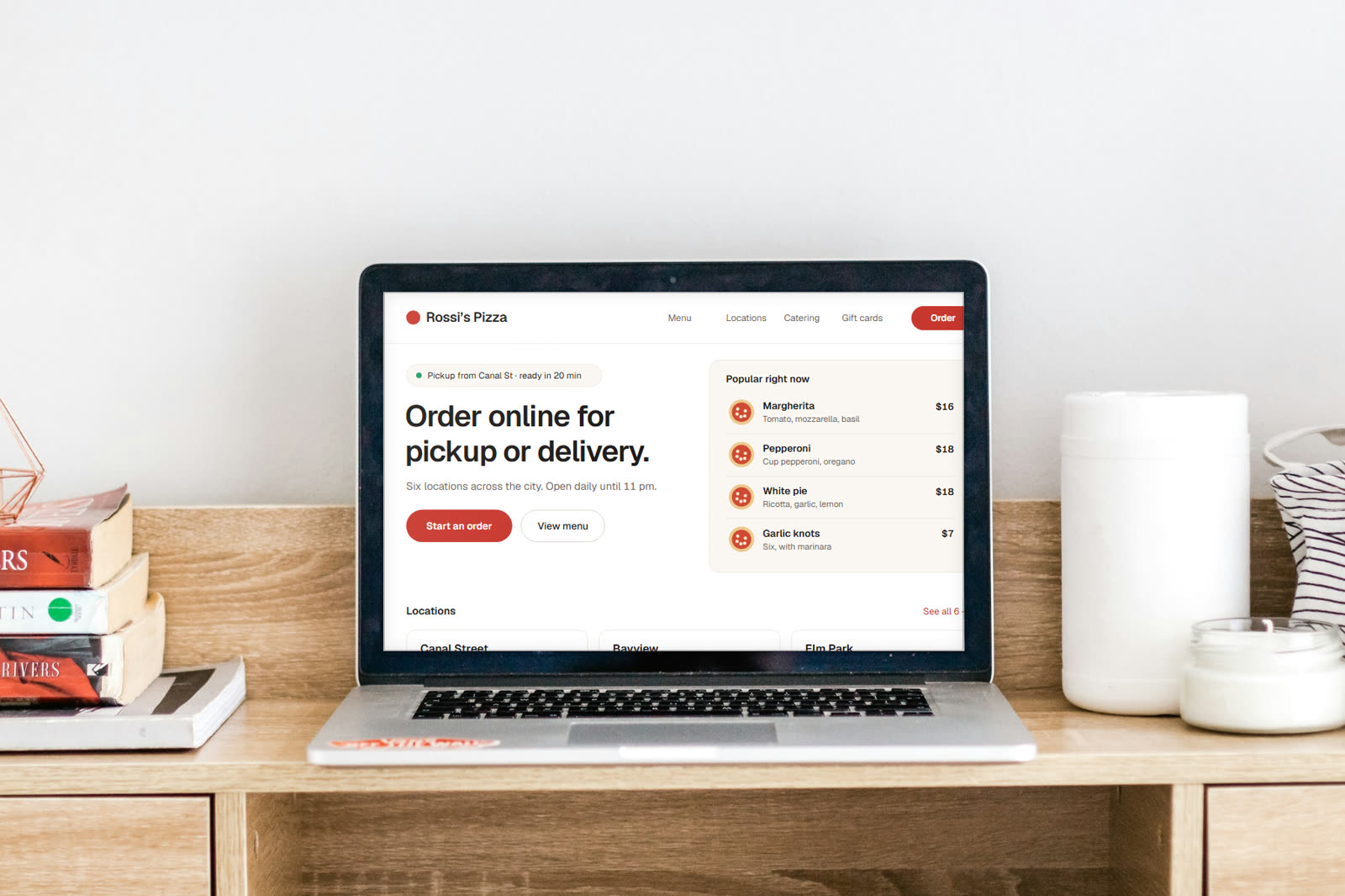 A laptop on a wooden desk showing a restaurant ordering site